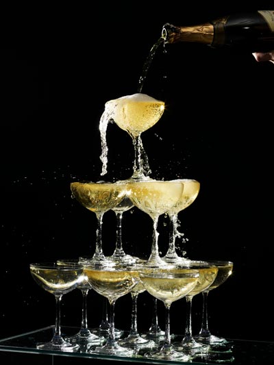 Sparkling wine being poured into a pyramid of glasses