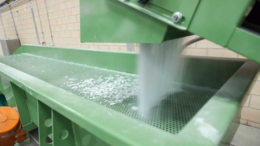 Fibreglass fragments being recycled by a machine