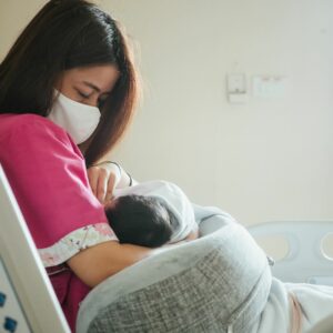 Mother wearing mask protection and newborn baby in hospital