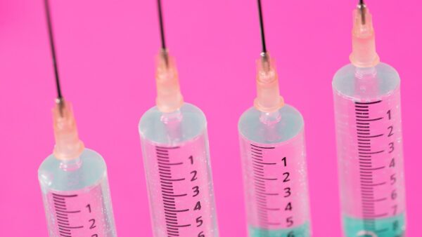Four syringes against a pink background