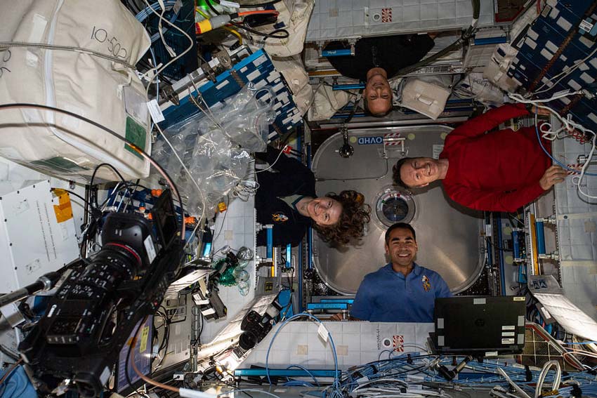 Photograph of four astronauts aboard the iss, each positioned at a different angle of 360 degrees