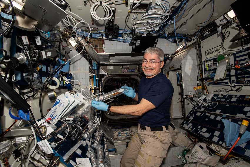 A middle-aged man with glasses using equipment on board the international space station