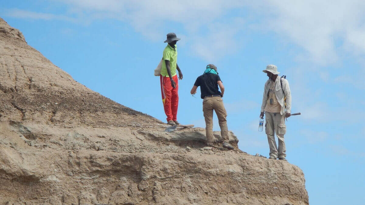 Three researchers standing on rock formation
