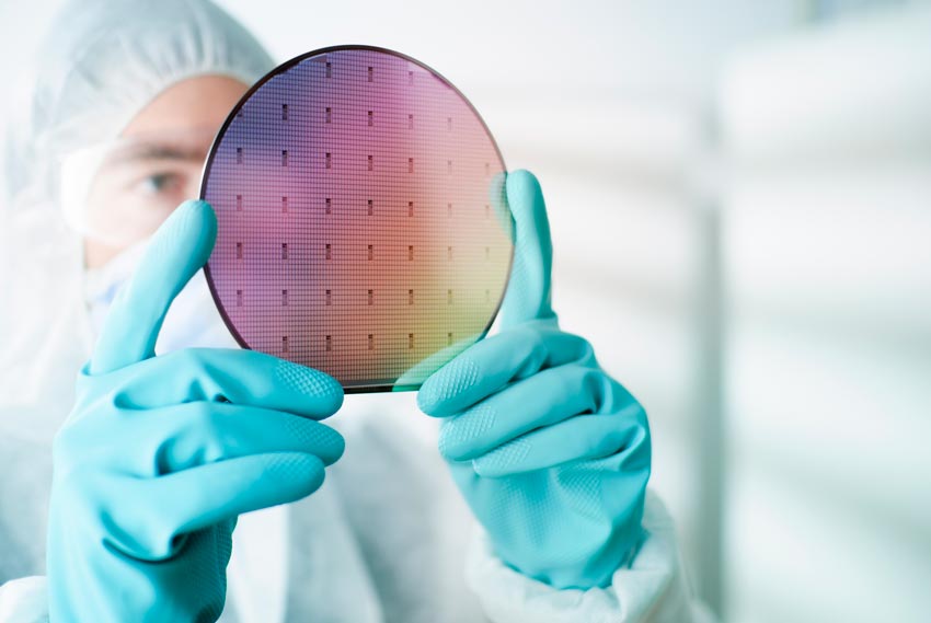 Scientist in ppe looking at a silicon wafer