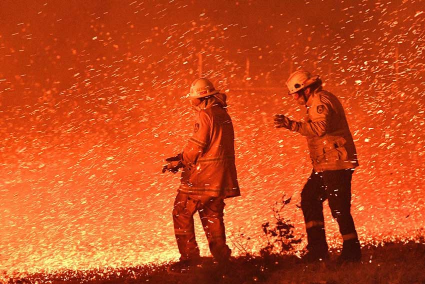 Firefighters surrounded by sparks being carried by the wind during a bushfire
