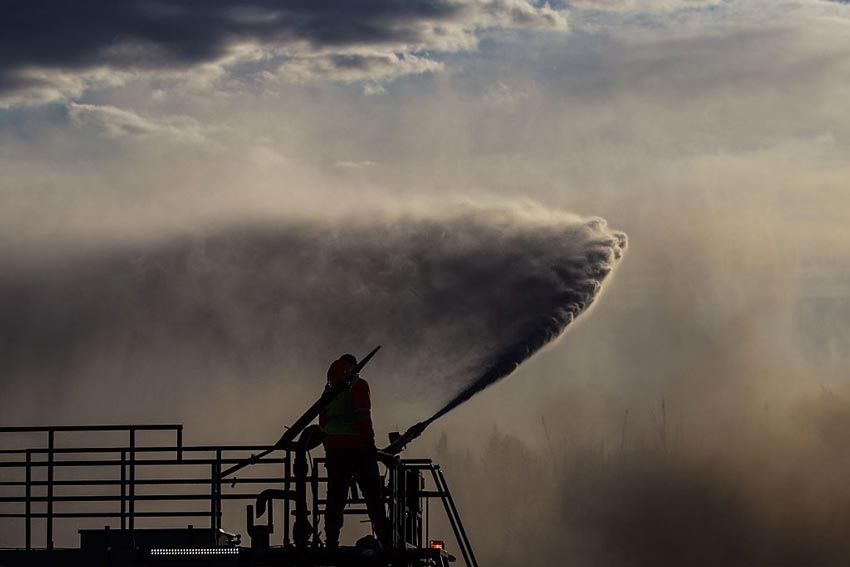 Firefighter health concept two firefighters on a platform working a fire extinguisher against a backdrop of smoke