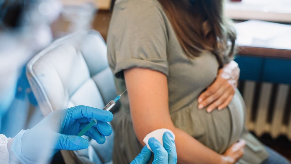 Doctor or nurse giving vaccine injection to pregnant woman