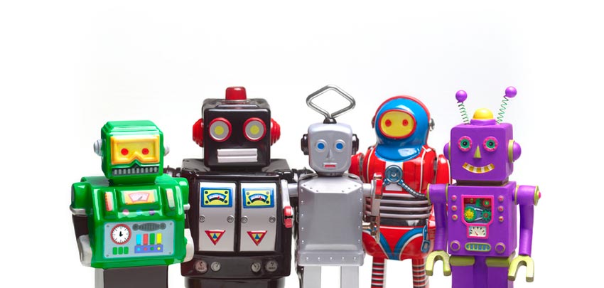Five different colourful toy robots standing in a crowd