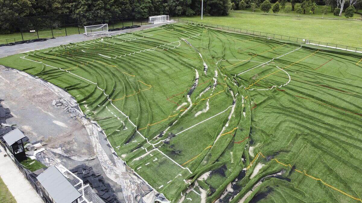 football field where the turf has been ripped and displaced by floodwaters