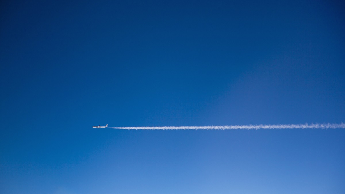 plane flies across a blue sky