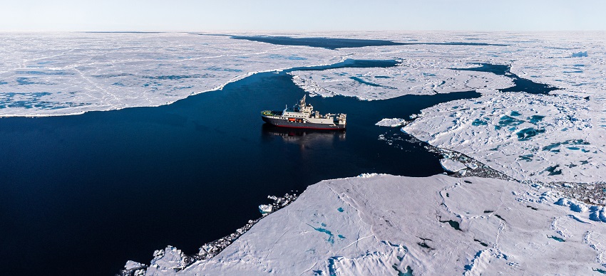 A ship floats between sea ice in the arctic ocean