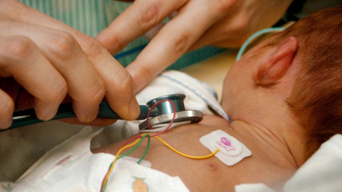 closeup of a doctor using a stethoscope on a newborn baby