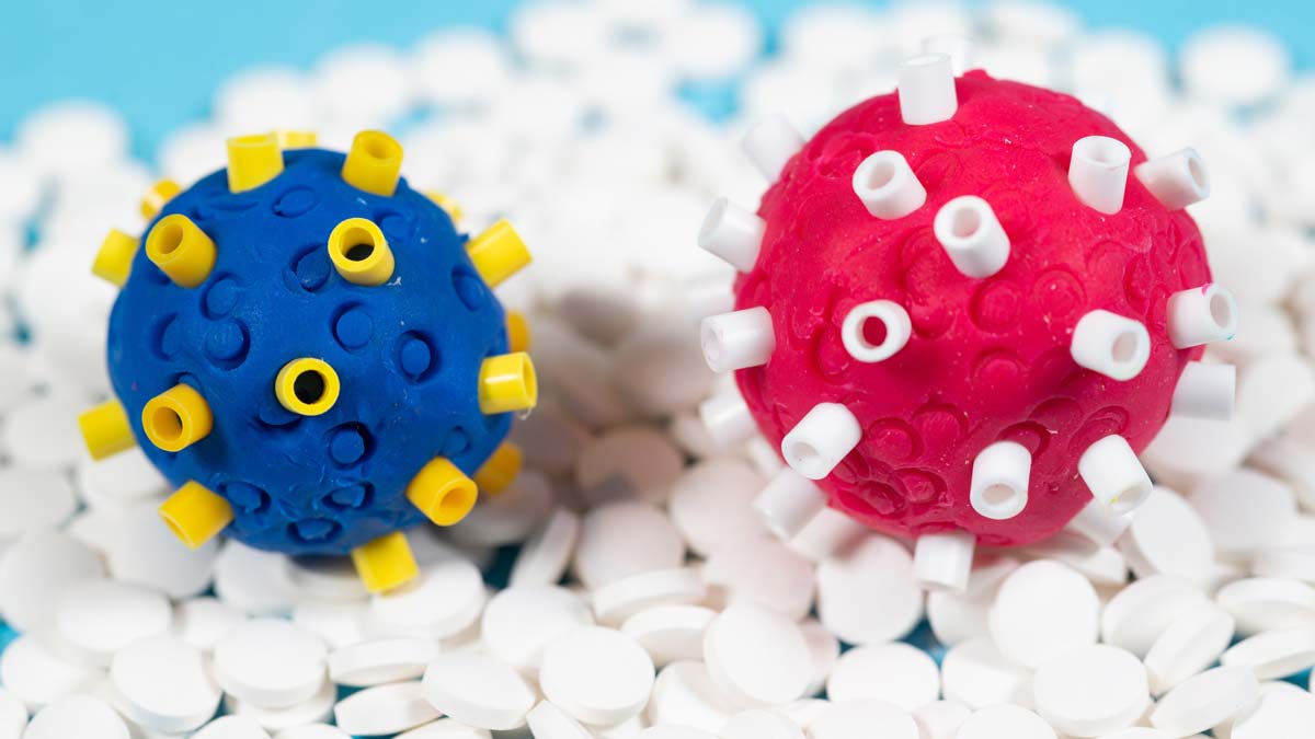models of two covid-19 variants sitting on a background of pills