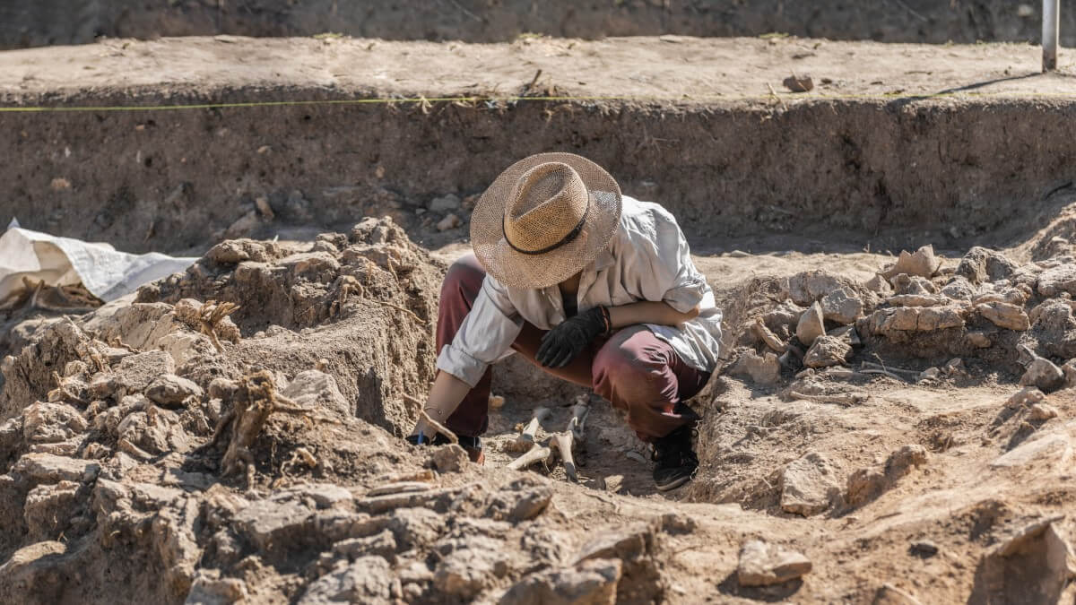 archaeologist at an excavation with face turned away from the camera