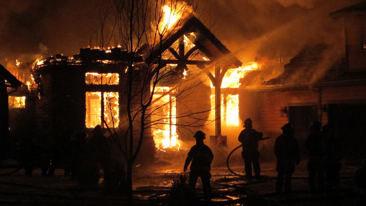 firefighters working to put out a house on fire at night