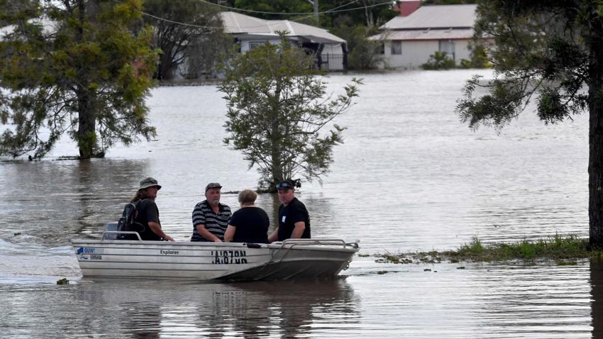 Four people sitting in a boat in a flooded street