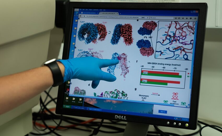 Finger points to screen with 3d models of proteins on it