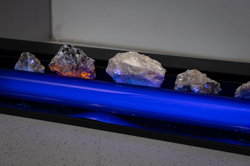 Four rocks on top of a uv lamp, three have bright white spots while one appears to be glowing orange from within