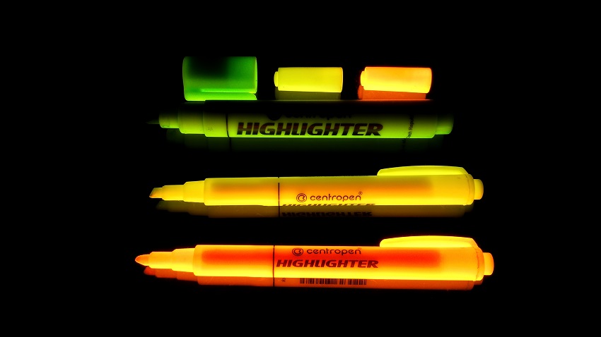 Three highlighters and caps glowing in the dark