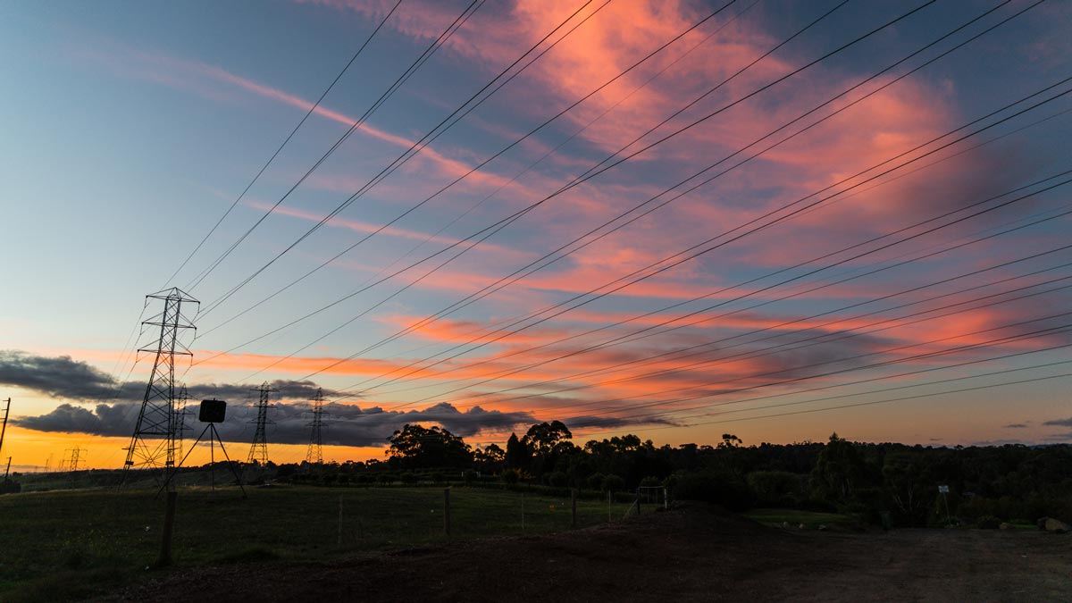 what is the grid concept photograph of a pretty sunset sky with pink cloud and pylons and electricity lines visible