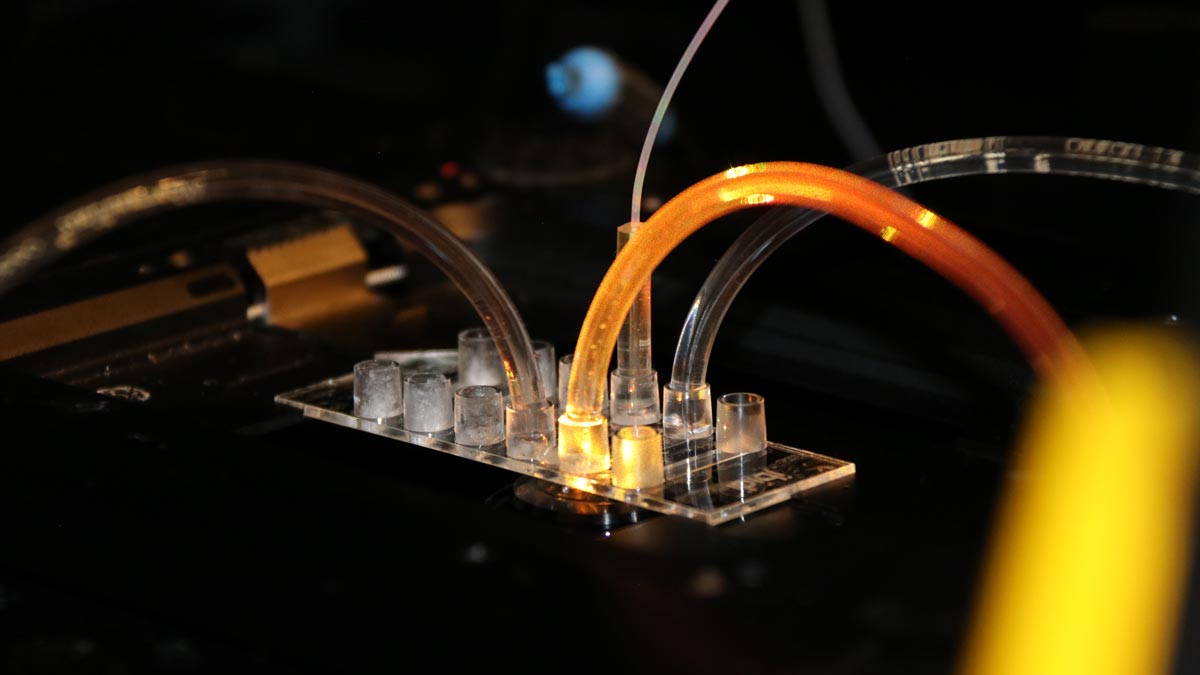 photograph of the nanotechnology a darnk background and illuminated tubes feeding into a device