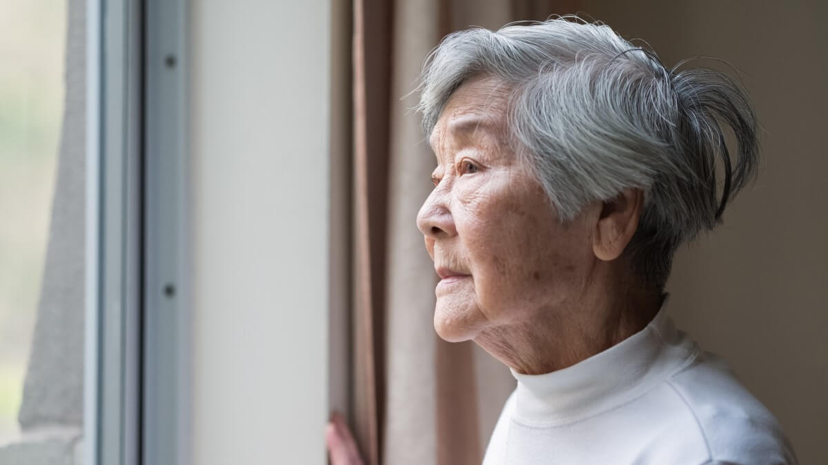 alzheimer's disease in women concept an elderly east asian woman with short hair gazing out of a window
