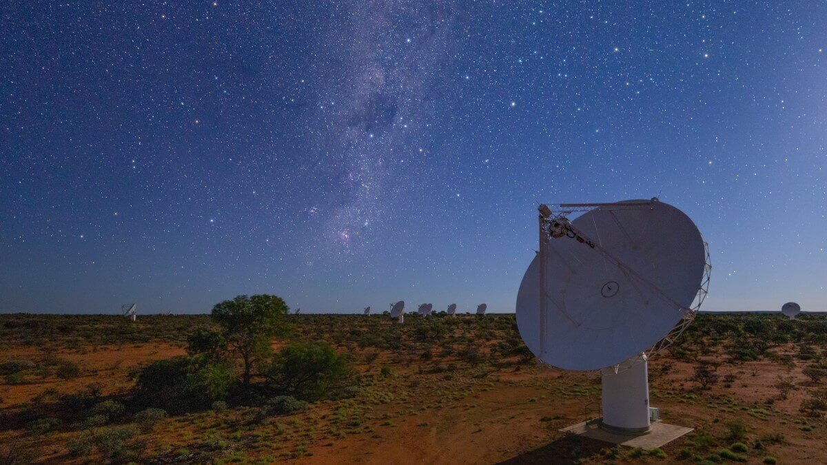 six telescope dishes in a red and green desert under a blue and starry sky