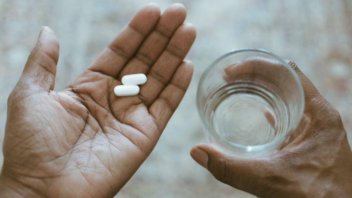 hands holding antidepressant pills and glass of water