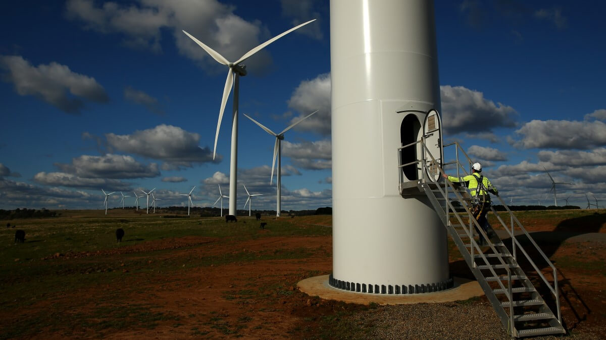 technician climbs up stairs to the base of a wind turbine at a wind farm