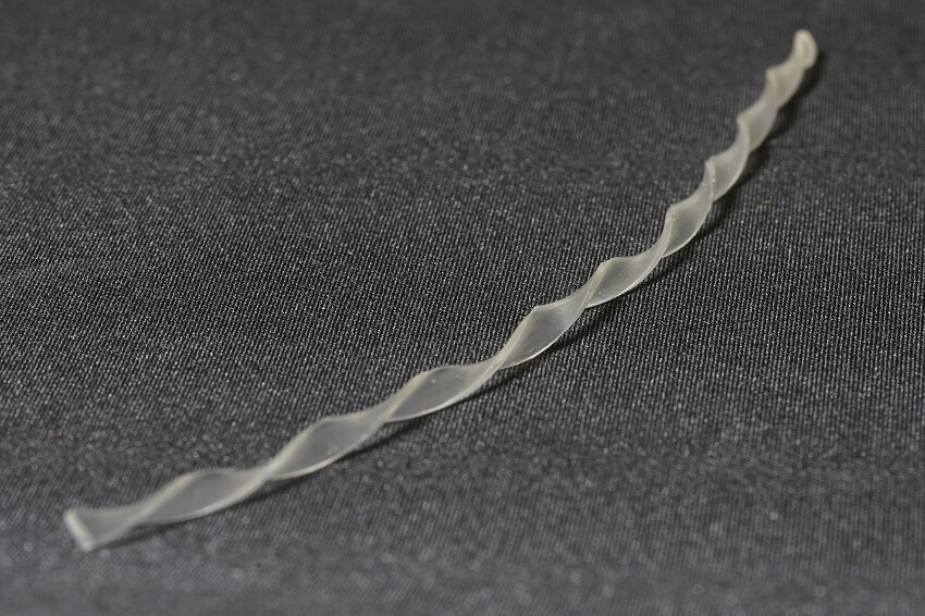 Translucent twisted strip of plastic-like substance on grey carpet
