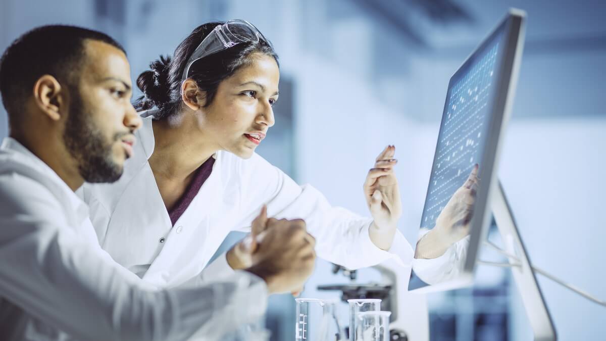 sex and gender data concept a male and female scientist in lab coats looking at genetic data on a computer screen