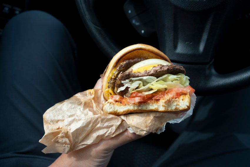 Pfas concept a man holding a hamburger in a greaseproof wrapper
