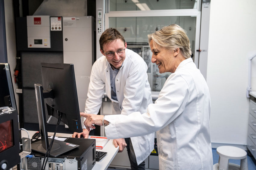 Seagrass scientists a man with glasses and woman with short blonde hair wearing lab coats and looking at a computer screen