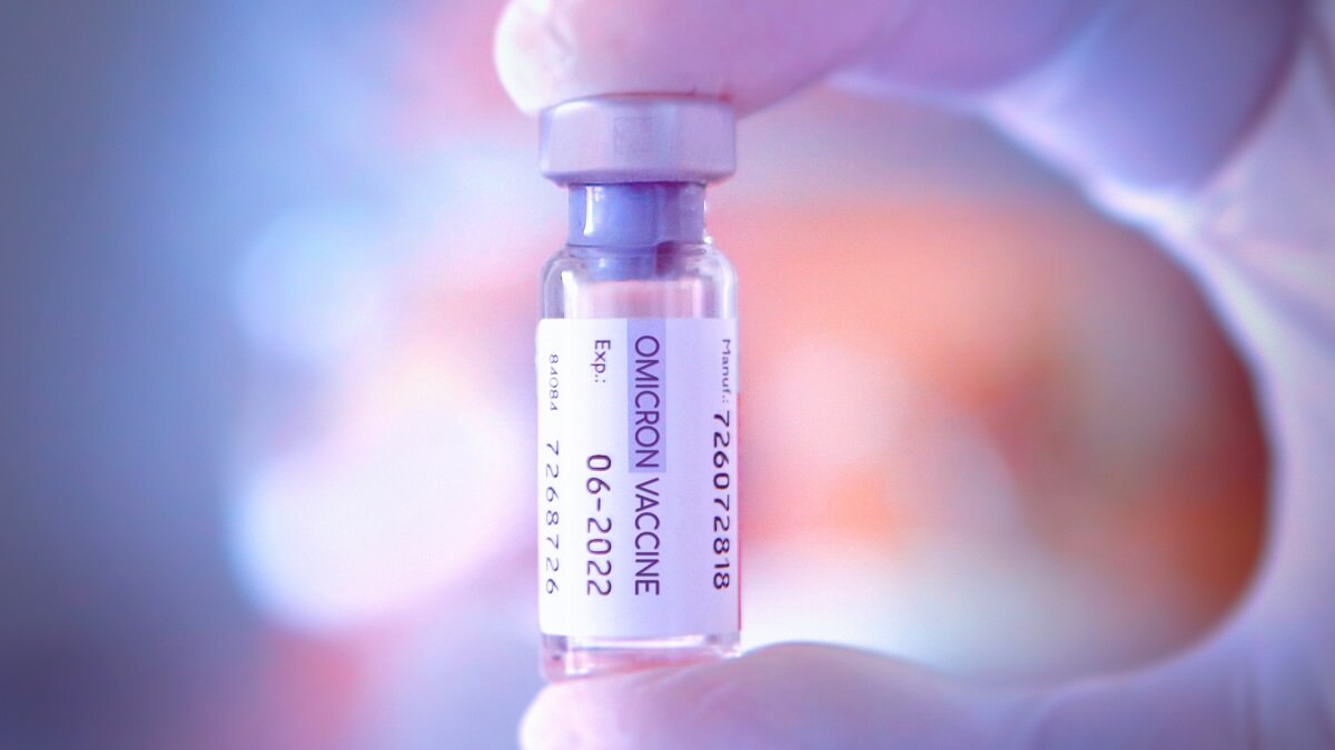 Hand holding a phial labelled "Omicron vaccine"