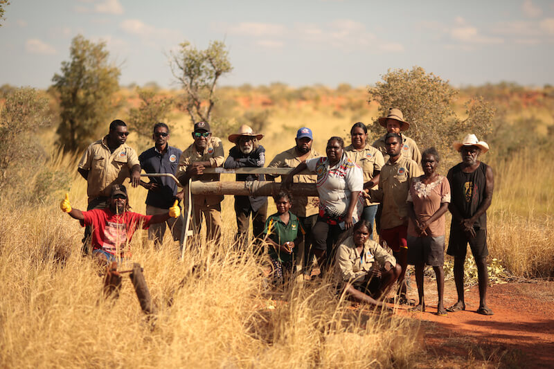 Group of 15 rangers standing in outback around a fence