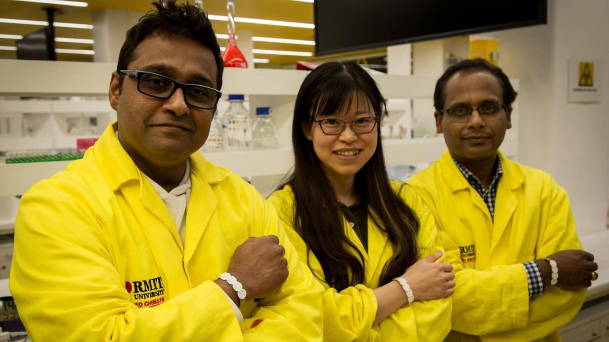 Three researchers in yellow lab coats