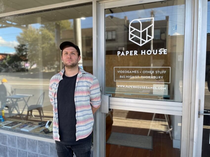 Terry burdak stands outside glass doors labelled paper house