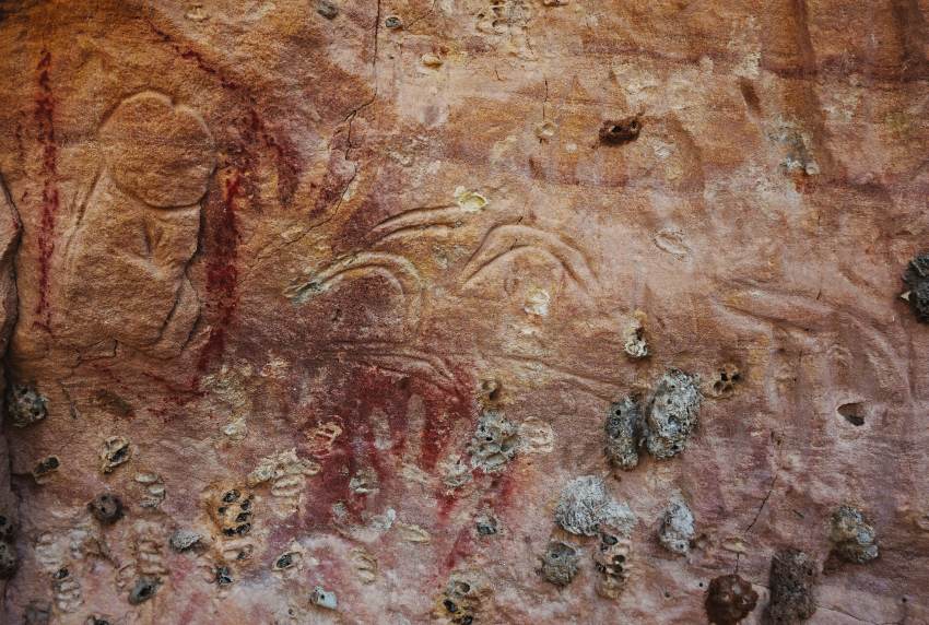 Marra wonga rock art depicting penis and boomerangs carved into rock, ochre-painted hands over the top