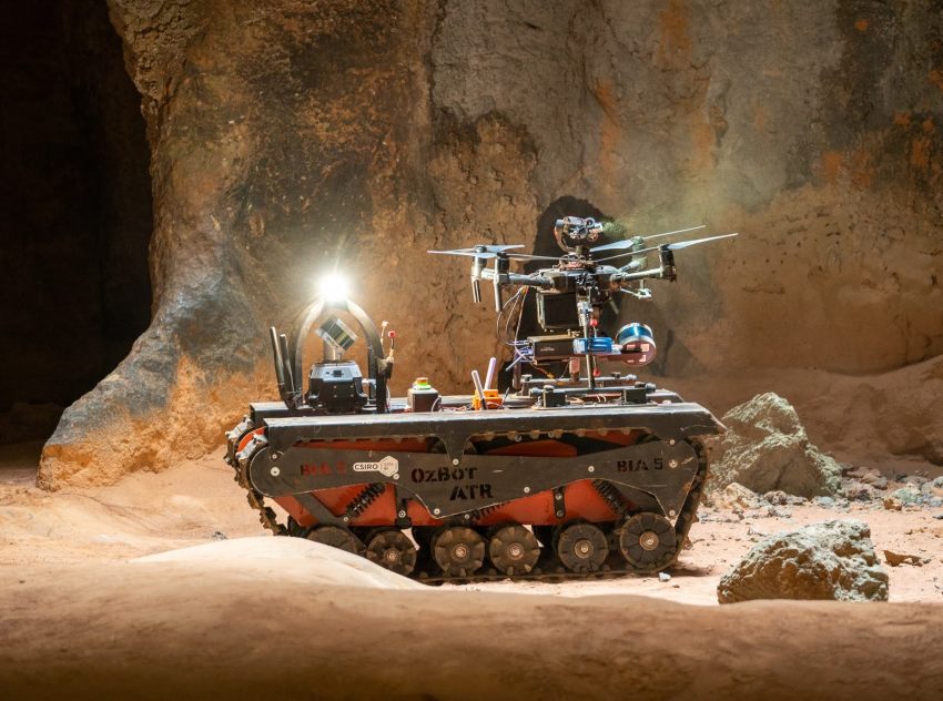 Tracked robot in a cave with a small drone on top