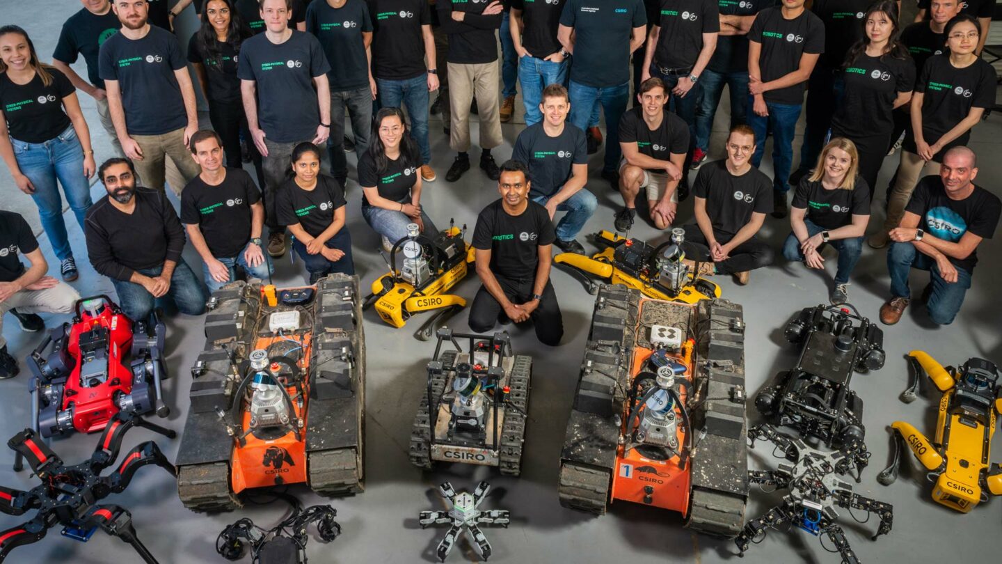 group shot of robotics team, two dozen people and 22 robots
