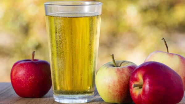 glass of cider outside with apples
