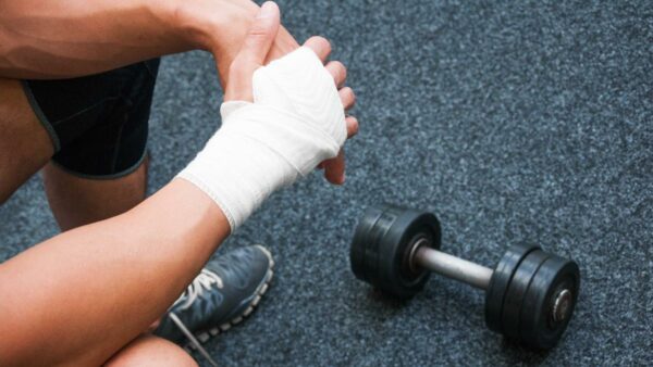 person with broken wrist immobilised in bandage and dumbbell for exercising other limb