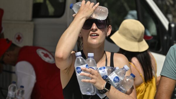 A woman cools off with cold bottles of water, distributed by the Hellenic Red Cross near the Acropolis in Athens on July 20, 2023