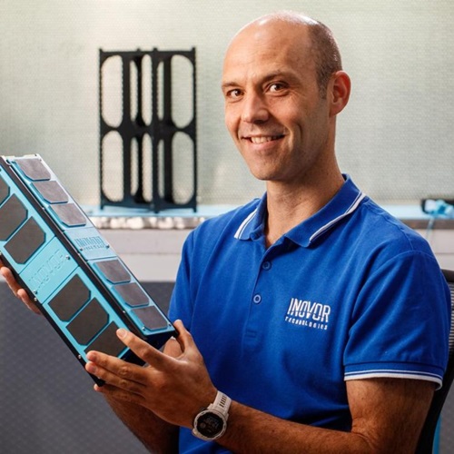 Man in blue shirt holding a satellite the size of a lunchbox