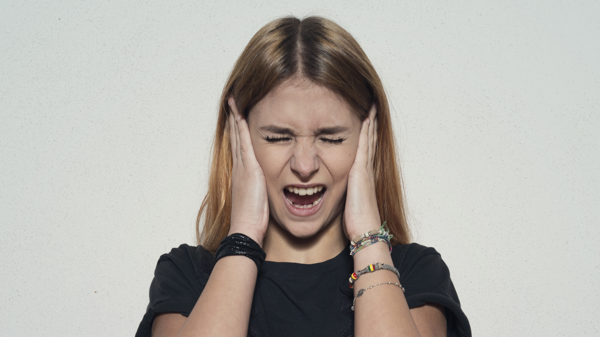 An irritated woman blocks her ears.