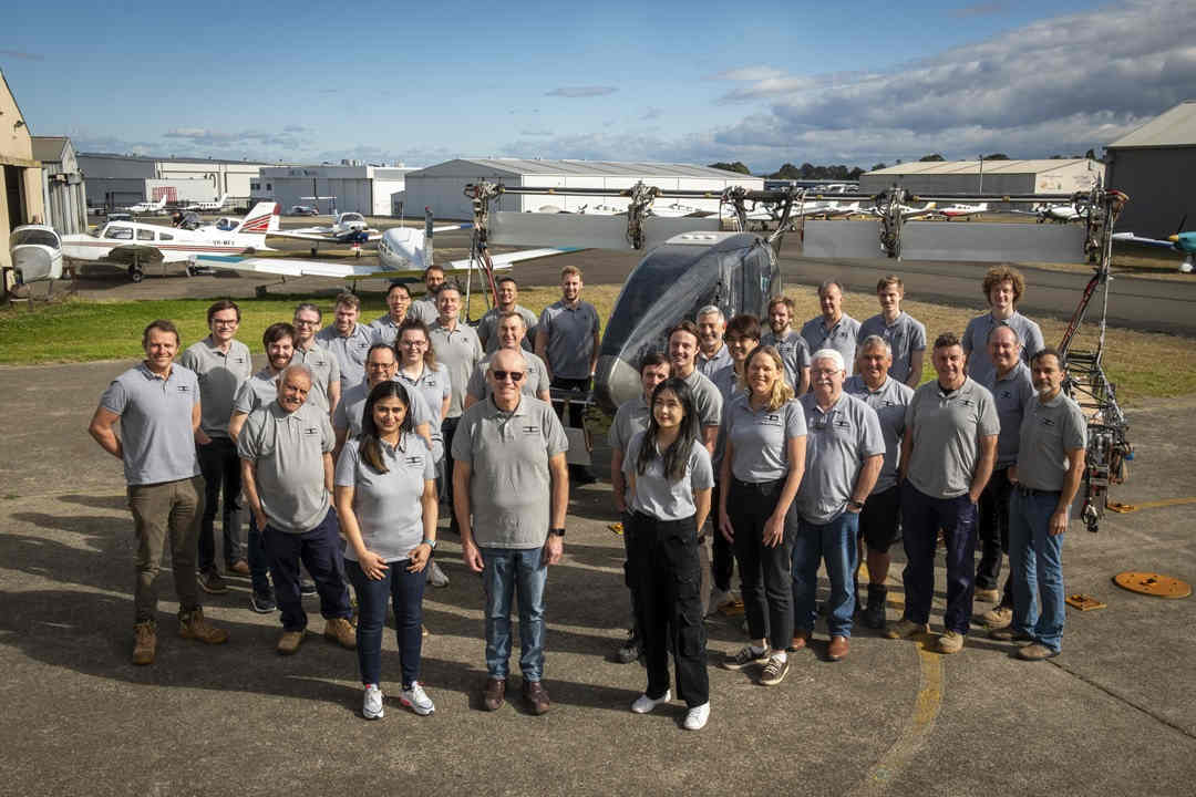 Lots of people in grey t-shirts stand in front of electric flying vehicle amsl aero