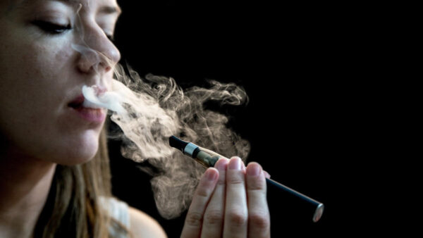Close up of a woman inhaling from an electronic cigarette vaping black background