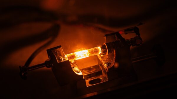 Photograph of a current being passed through a substance, heating it to emit yellow/orange light
