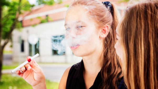 Preteen girl tries e-cigarette with her friend