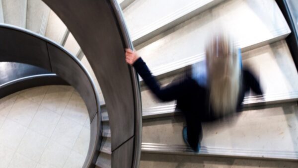 Photograph of a blurred person walking up a spiral staircase